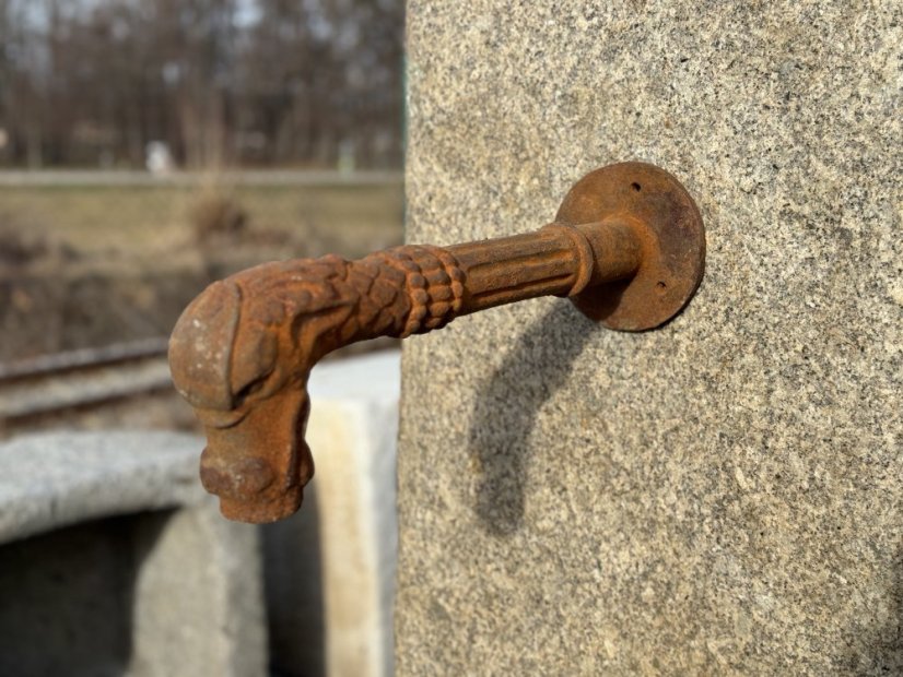 Železný výtok vody ze sloupu – detail chrliče na žulovém sloupu